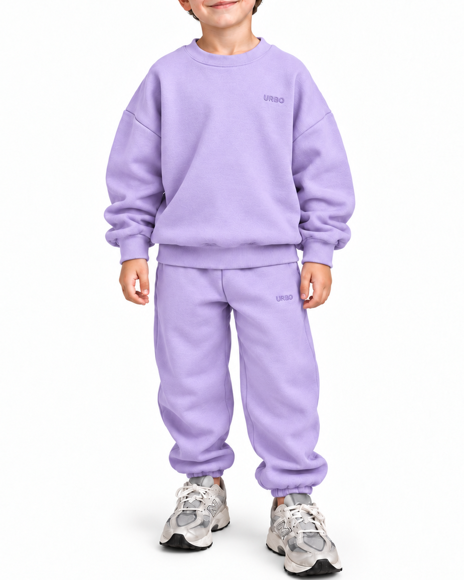 A young boy wearing a matching lavender sweatshirt and jogger pants set, standing against a plain white background.