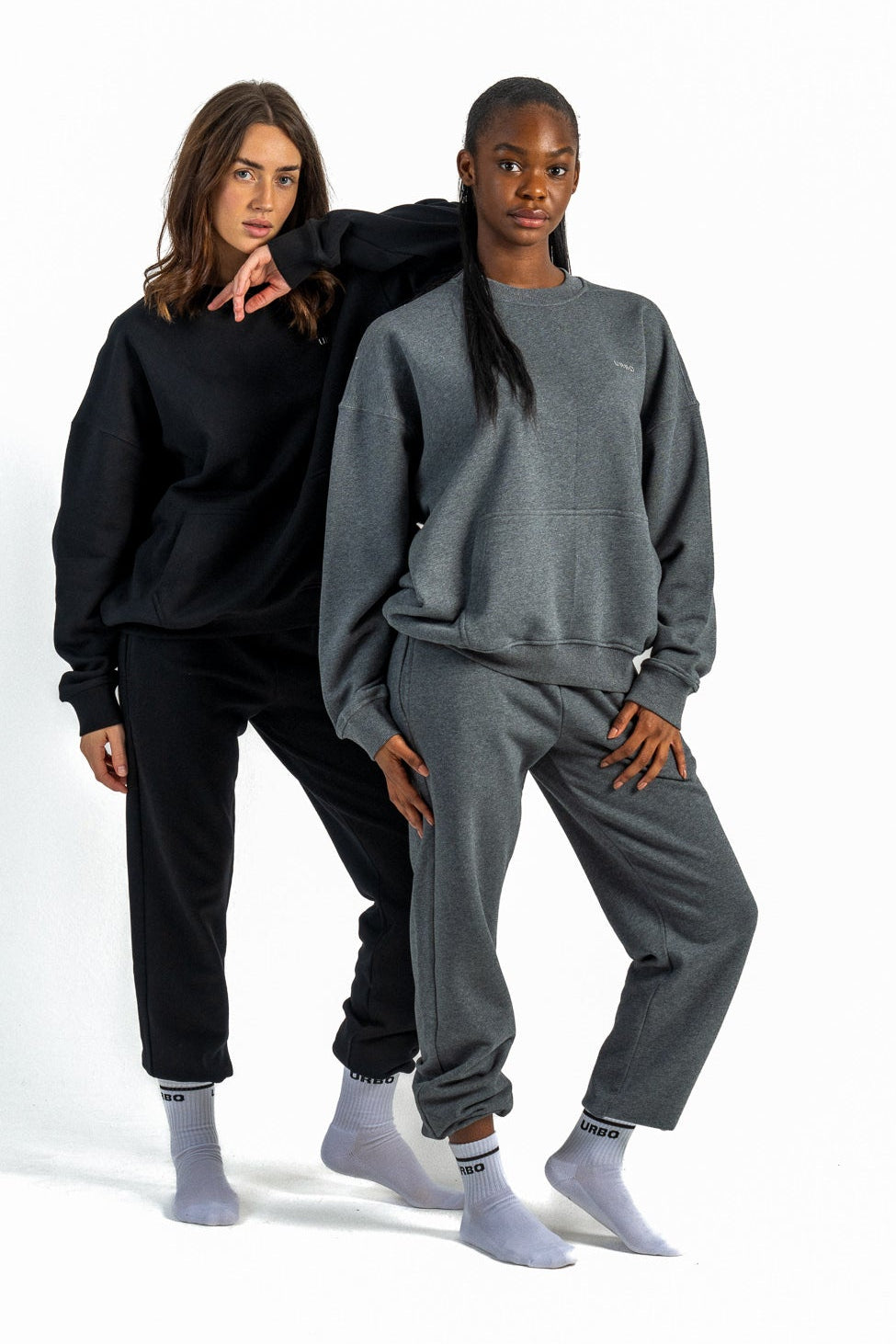 Two people wearing matching black and gray sweatsuits on a white background