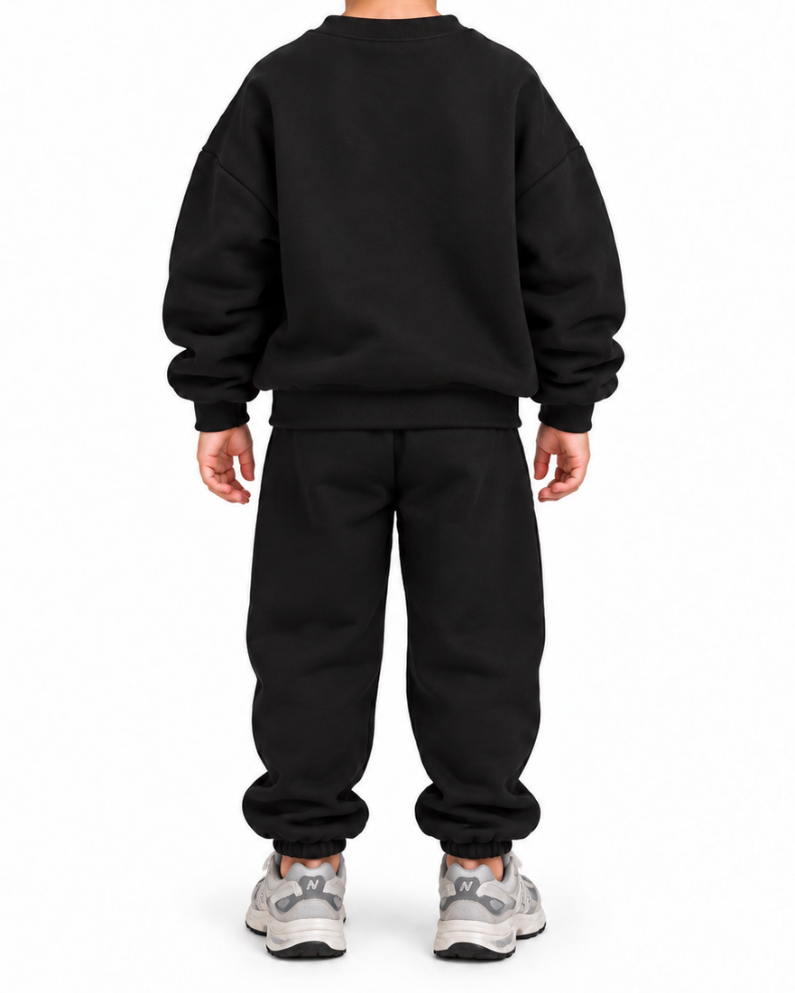 A child viewed from the back wearing a black crewneck sweatshirt and matching black sweatpants, paired with gray and white sneakers, against a plain white background.