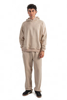 Person wearing a beige hoodie and pants set on a white background