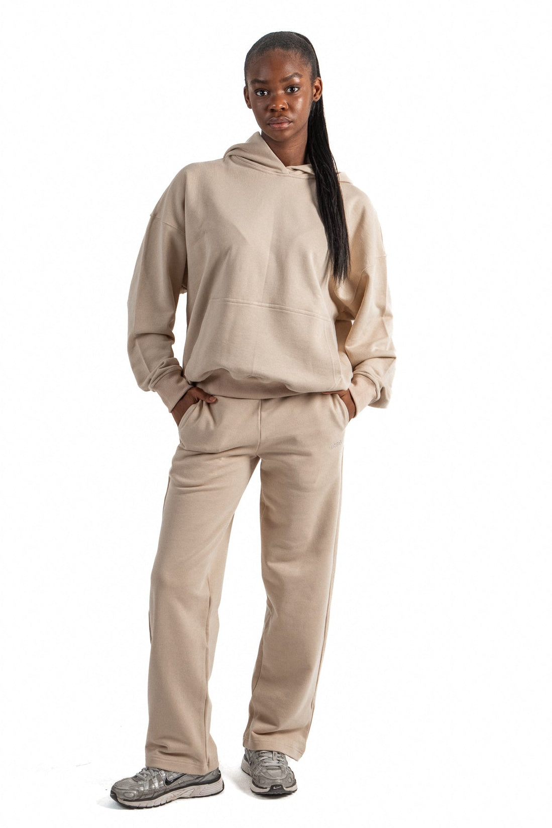 Person wearing a beige tracksuit on a white background