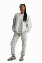 Person wearing a gray sweatshirt and pants set on a white background