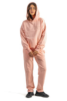 Person wearing a pink hoodie and pants set on a white background