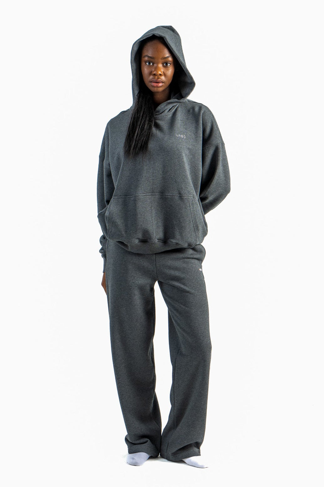 Person wearing a gray hoodie and pants on a white background